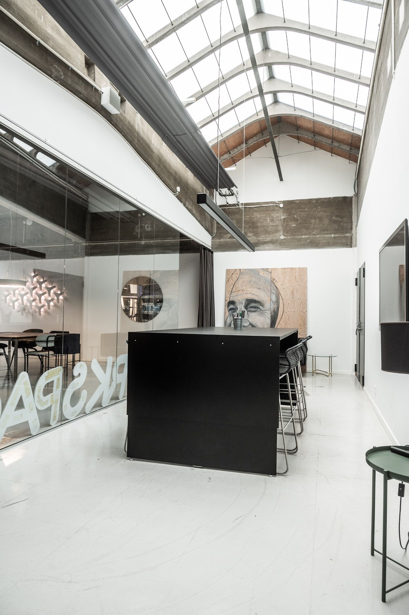 Raffinaderivej kontor med loftsruder og en stor møbelgruppe med stolpelampe og maleri på væggen