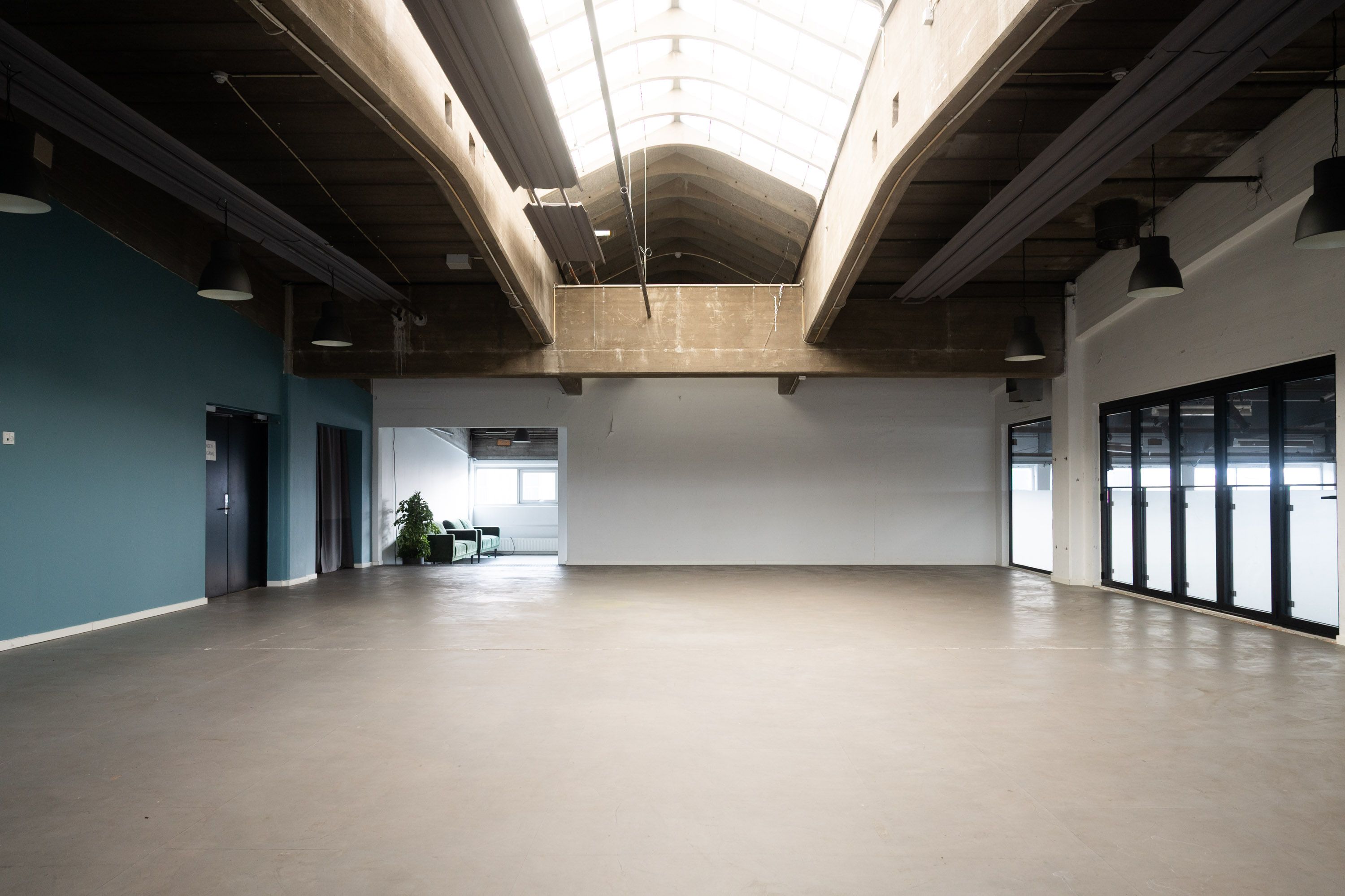 Kontor til leje i Råt og karakterfuldt kontor i de ikoniske spritfabrikker på Amager, midt i TAP 1 på Raffinaderivej. Moderne loft med lyseglas og hængelampe. Hvid og blå væg, og glasdøre og vinduer