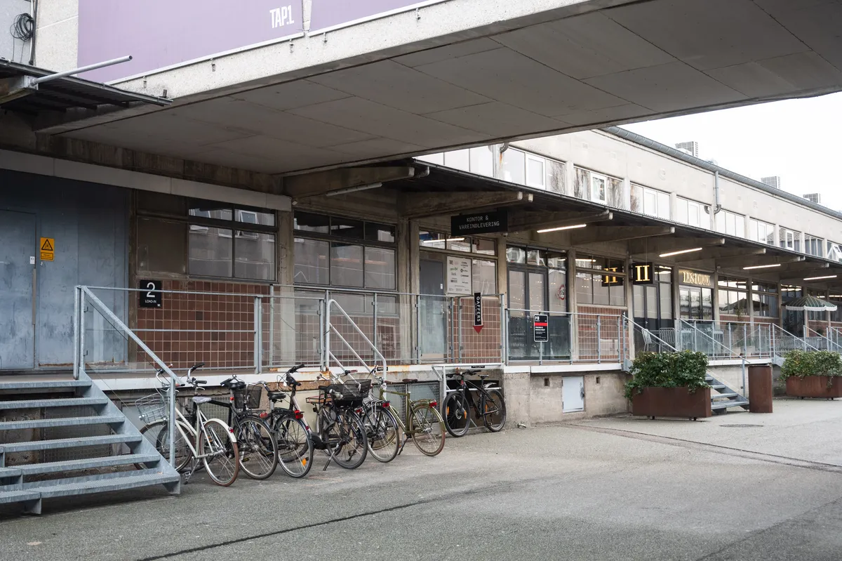 Rå og karakterfuldt kontor i TAP 1 på Raffinaderivej med flere cykler parkeret udenfor og en skrånende trappe til indgangen