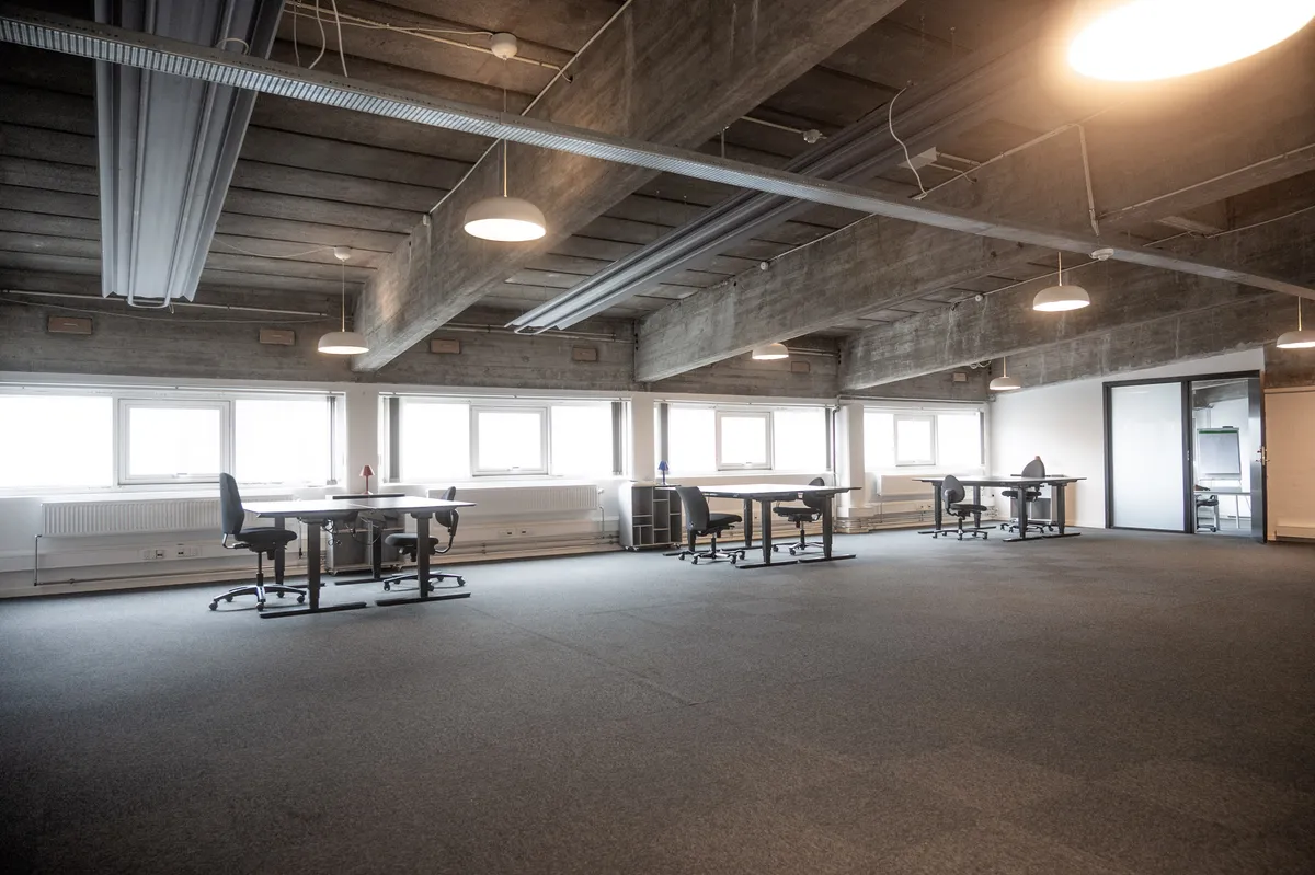 Kontor med lyse lofter og gulvbelægning samt møbler, der er arrangeret rundt om bordene
