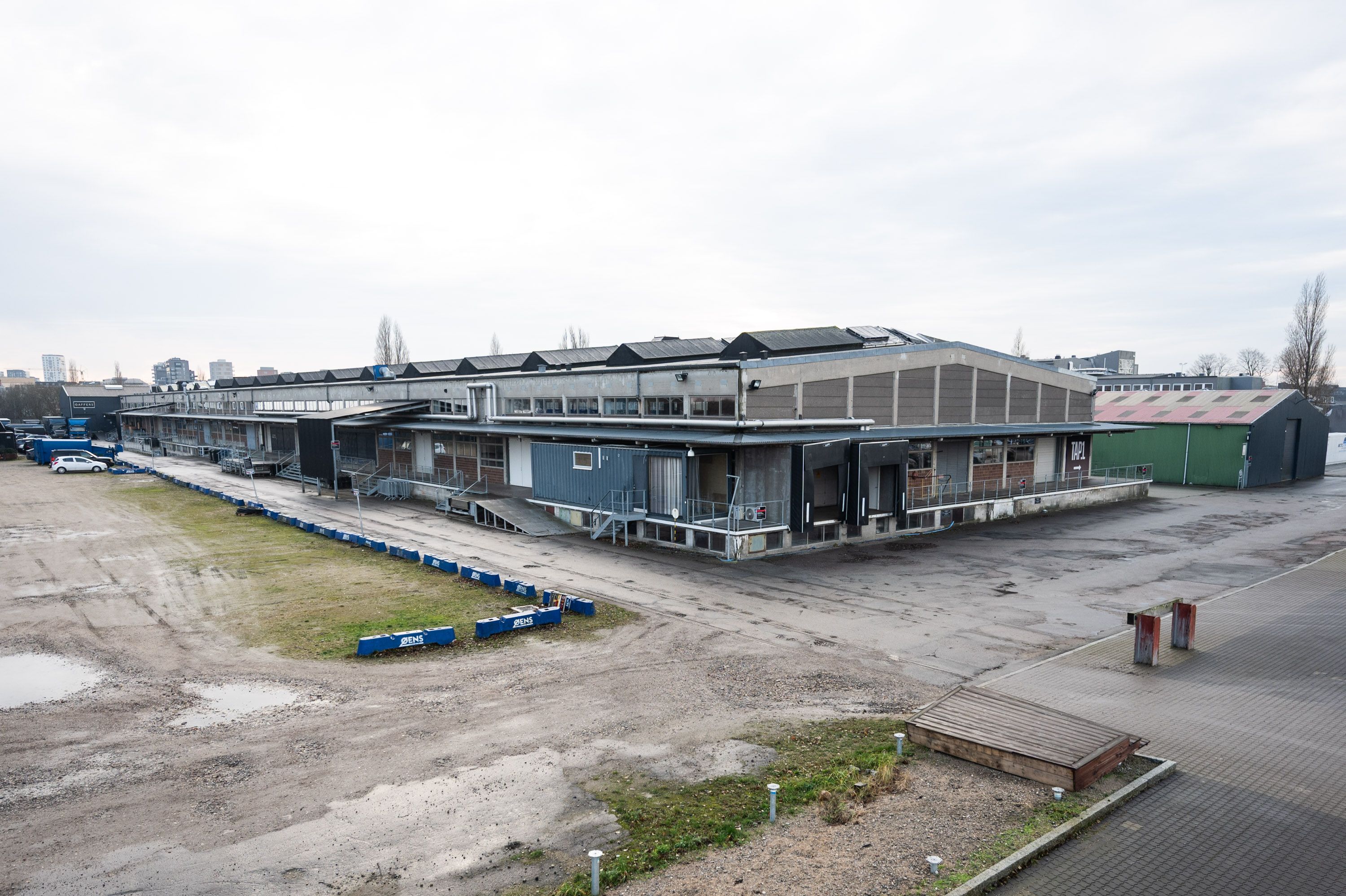 Rå og karakterfuldt kontor på Raffinaderivej med grønne tage, flere parkerede biler og to røde døre