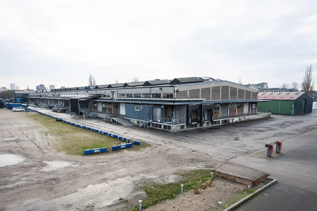 Rå og karakterfuldt kontor på Raffinaderivej med grønne tage, flere parkerede biler og to røde døre