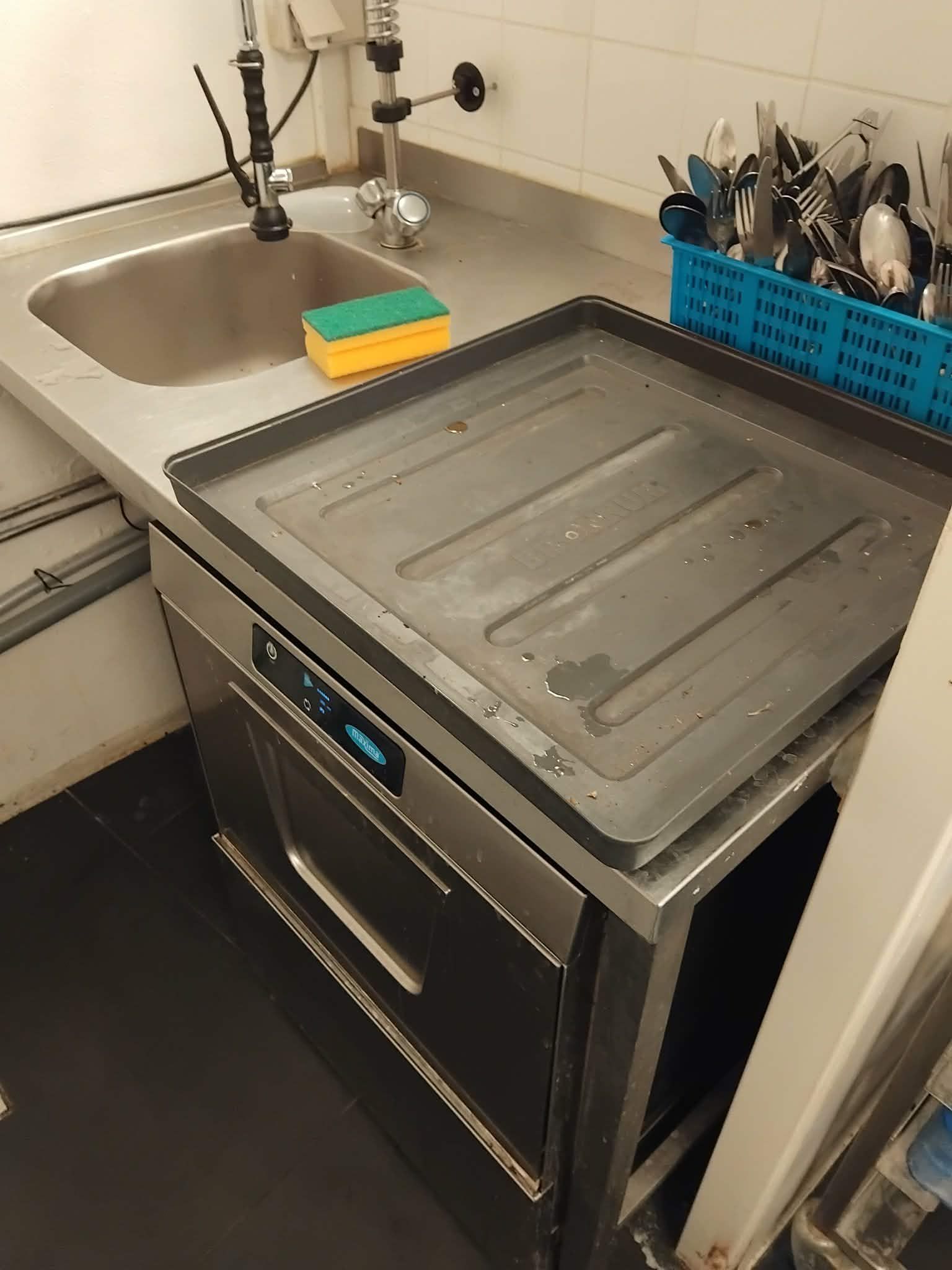 I en lille café er der en rusten komfur, en stor metalbakke og et rent vaskebækken med en skraber.