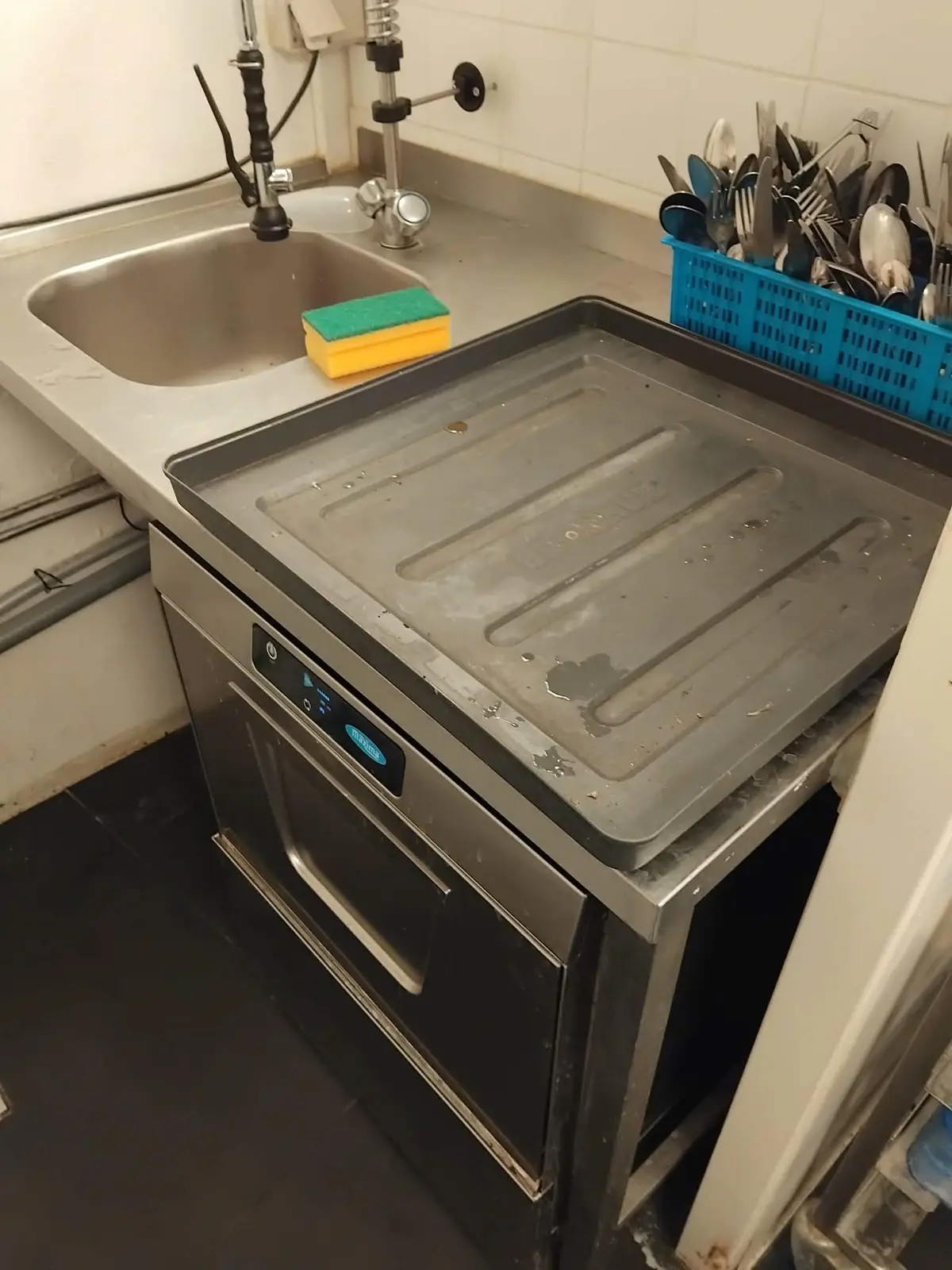 I en lille café er der en rusten komfur, en stor metalbakke og et rent vaskebækken med en skraber.