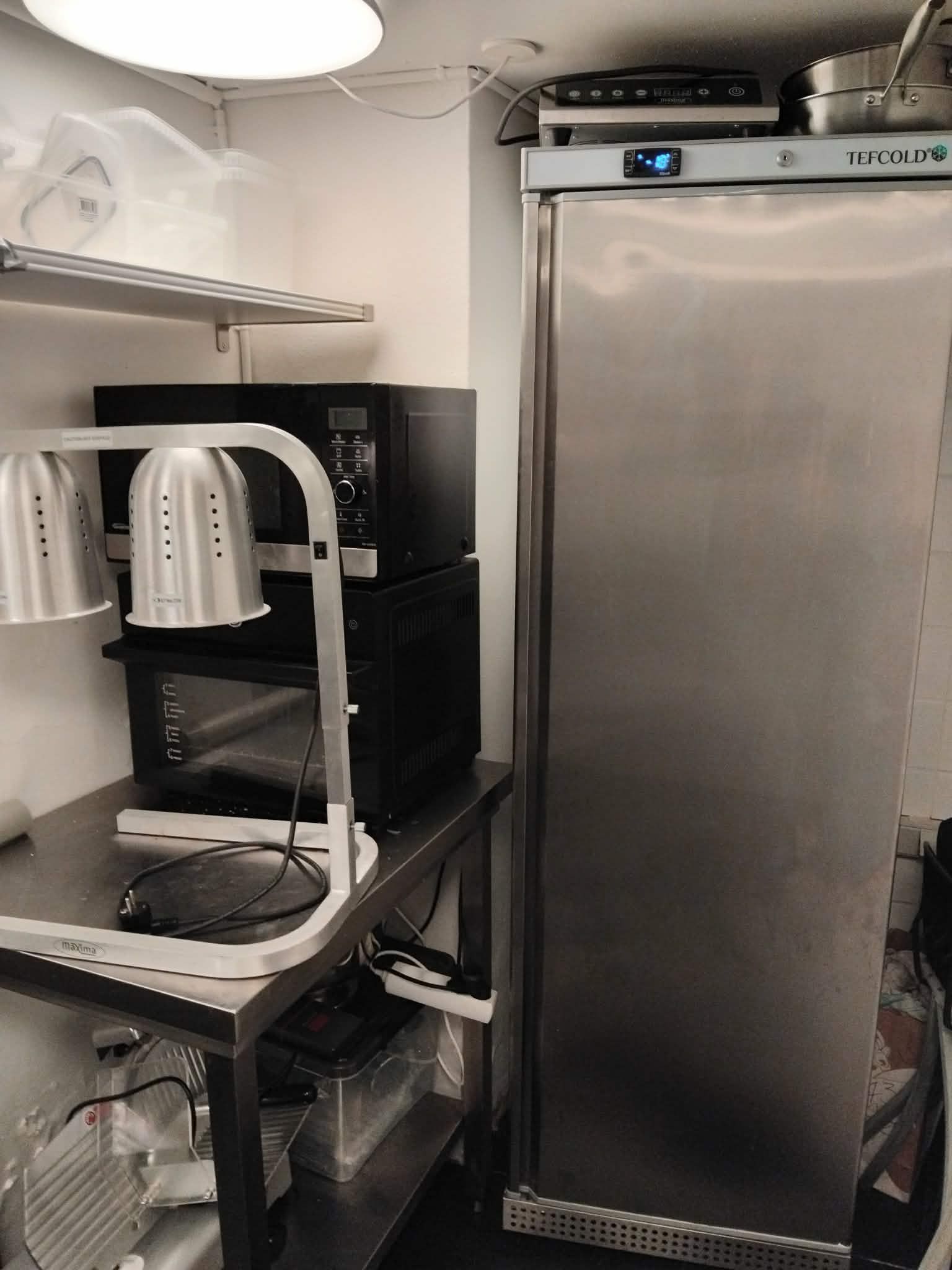 En stald med køleskab, mikroovn og kogeapparat samt andet køkkenudstyr i et caférum med mulighed for hurtig overtagelse