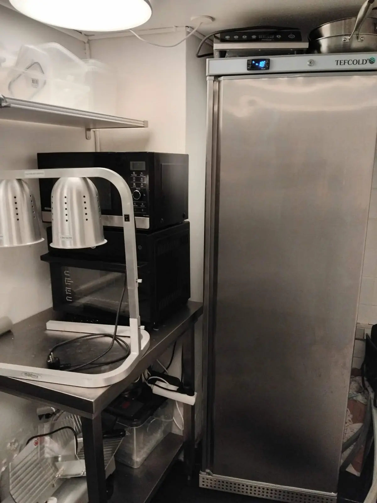 En stald med køleskab, mikroovn og kogeapparat samt andet køkkenudstyr i et caférum med mulighed for hurtig overtagelse