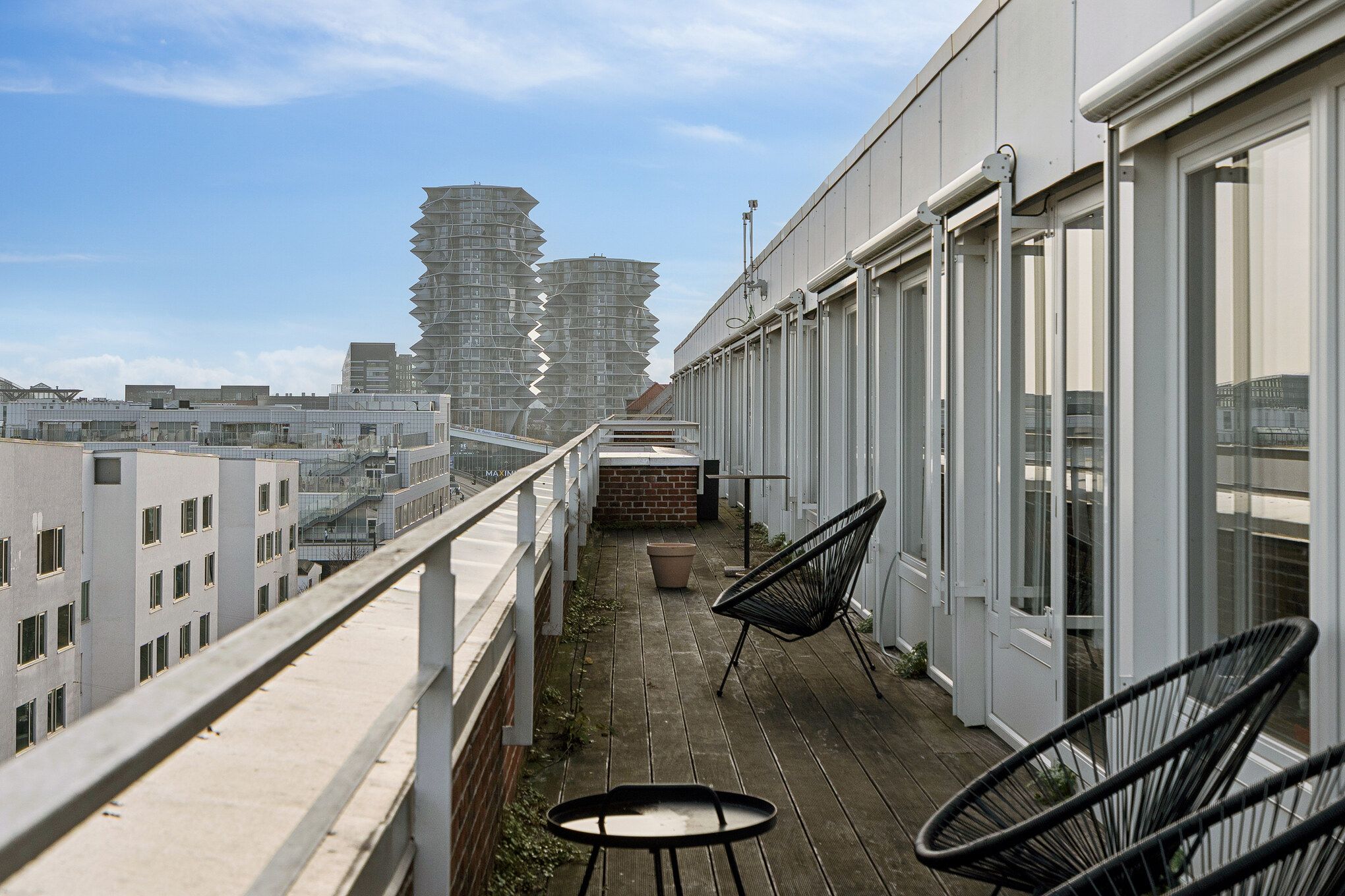 Privat terrasse med moderne møbler og en flot udsigt over byen. Kontorhus med hjørneterrasse og panoramaudsigt over Kødbyen. Møblerne er minimalistiske og skaber en afslappet atmosfære.
