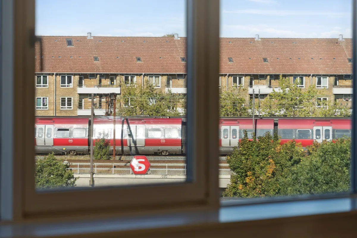 Et vindue med udsigt til en togspor med et tog og et stopskilt med bogstavet S