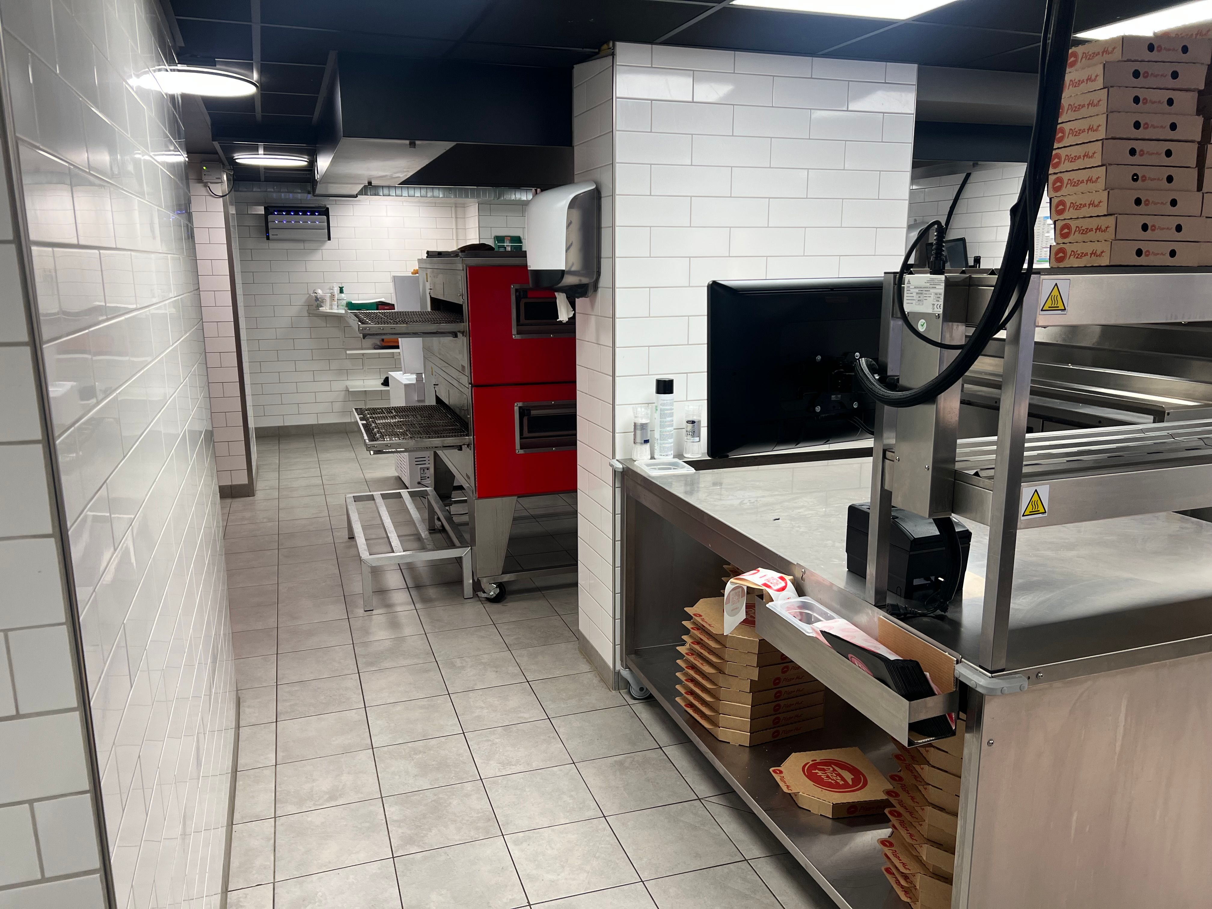 Take-away med røde ovne og Pizza Hut-kasser i et hvidt lokale med nye, lysegule gulvfliser