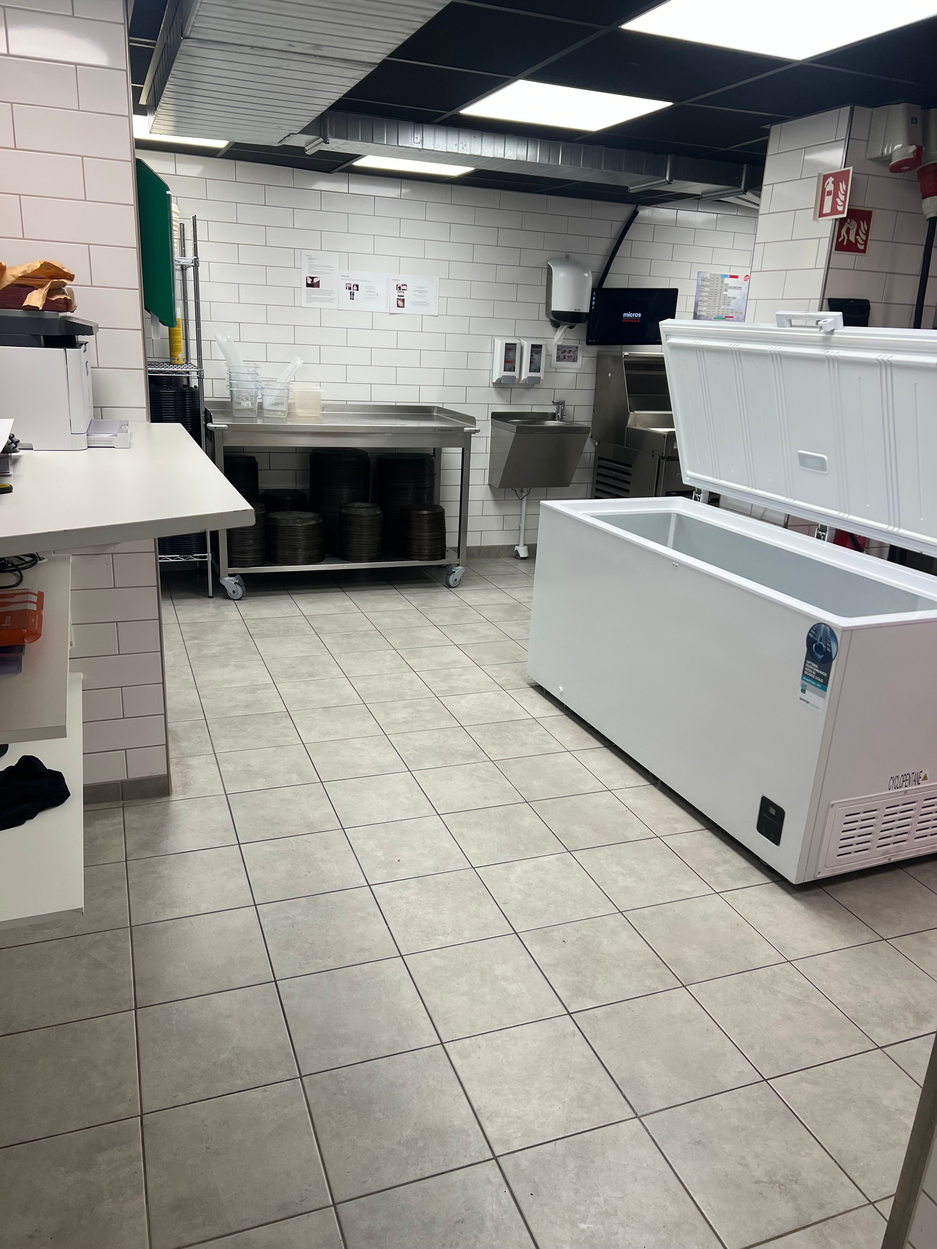 Et stort kommercielt køleskab og et bord med køkkenudstyr i et nyt kommercielt køkken til leje i Hørsholm