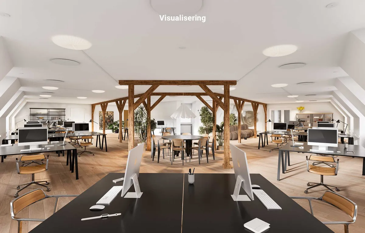 Kontor med moderne indretning, tre monitorer på hvert bord, åbent rum med lyse lofter, træbjælker og en stor rund lampe i loftet