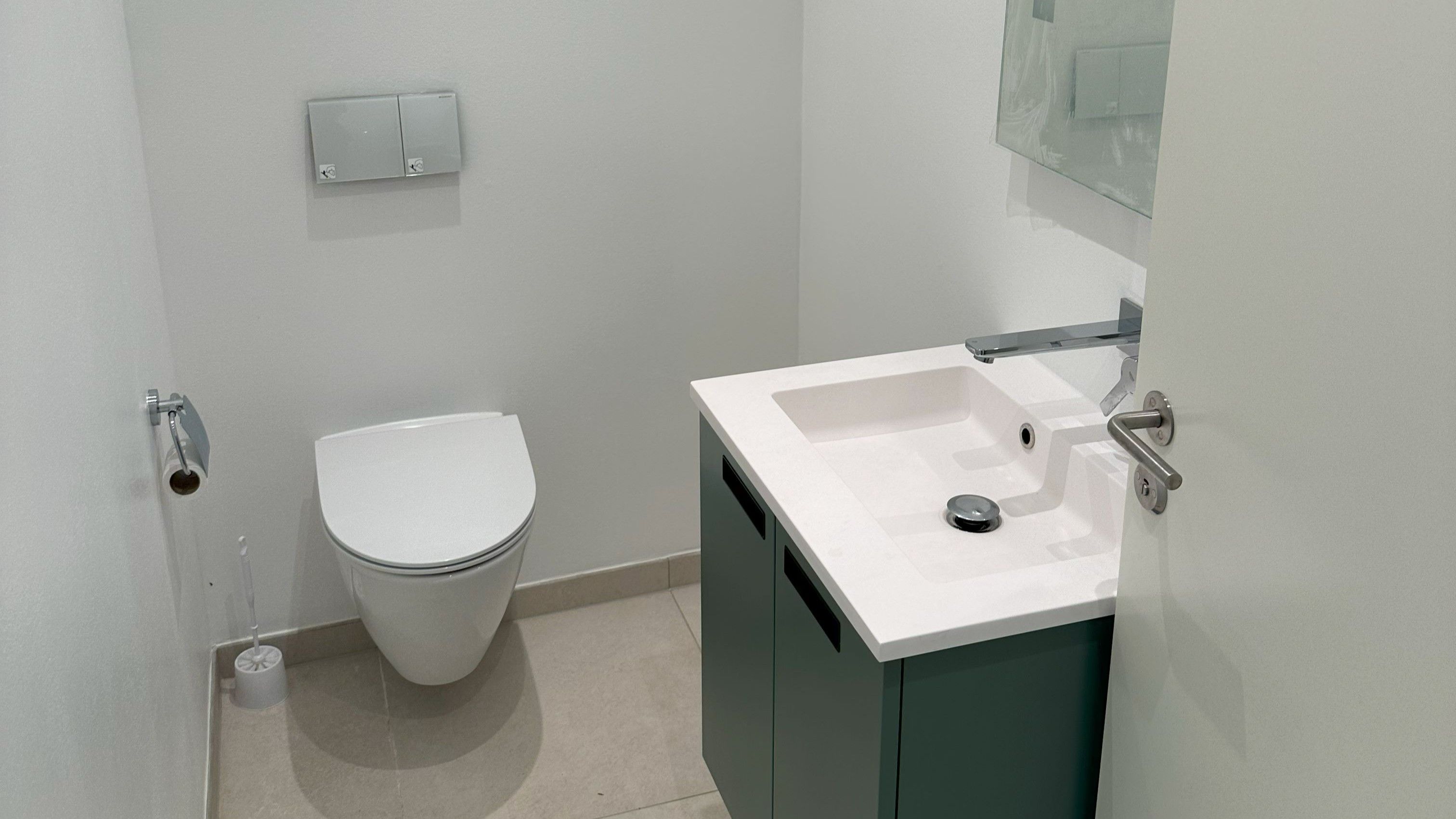 Et rent og funktionelt toilet med hvid toilet, hvidt vask og en moderne sølvfarvet vandhane