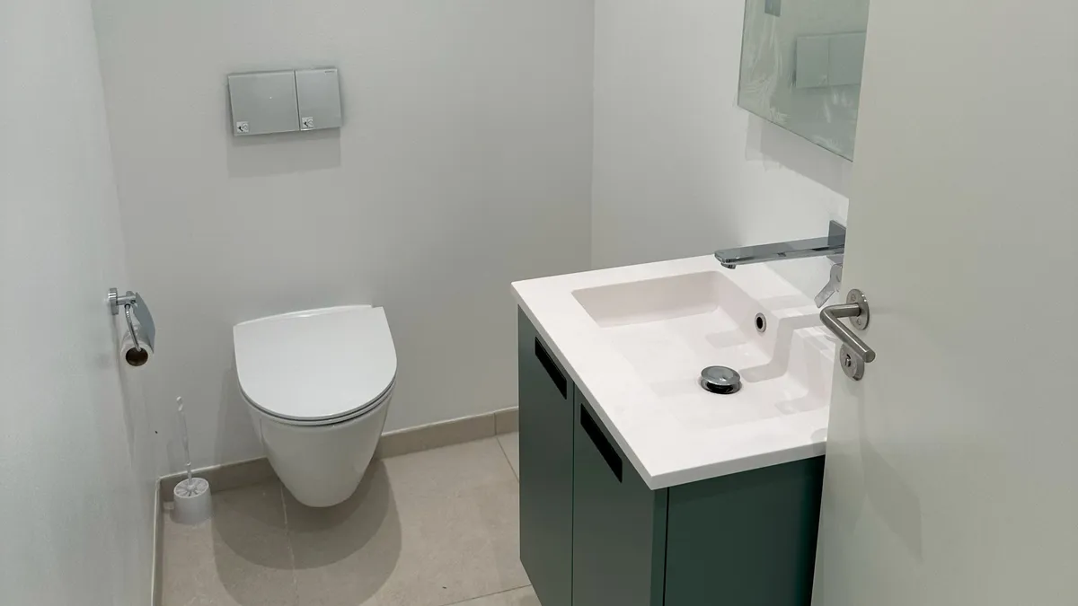 Et rent og funktionelt toilet med hvid toilet, hvidt vask og en moderne sølvfarvet vandhane