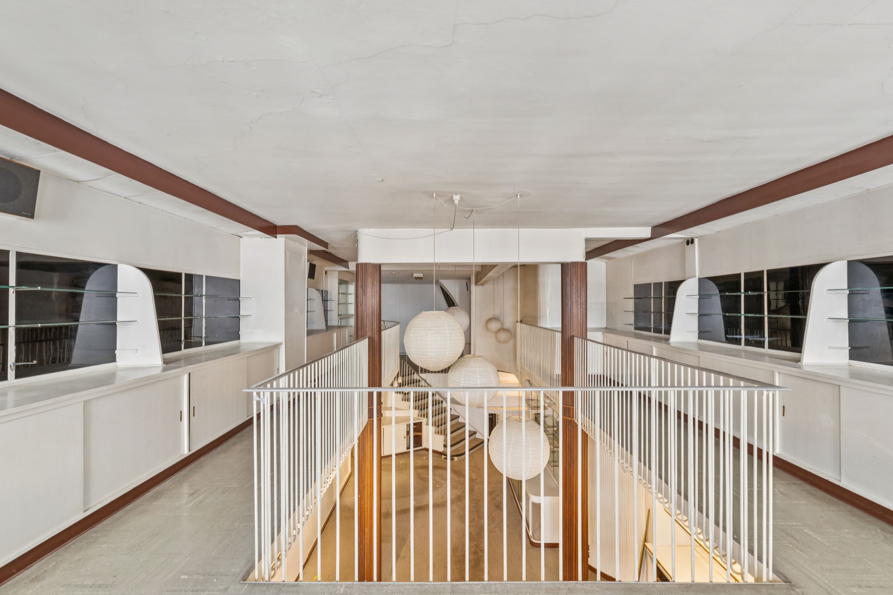 En stor indre atrium med hvide søjler og en hvid stige, hvor der hænger hvide lanterner i loftet