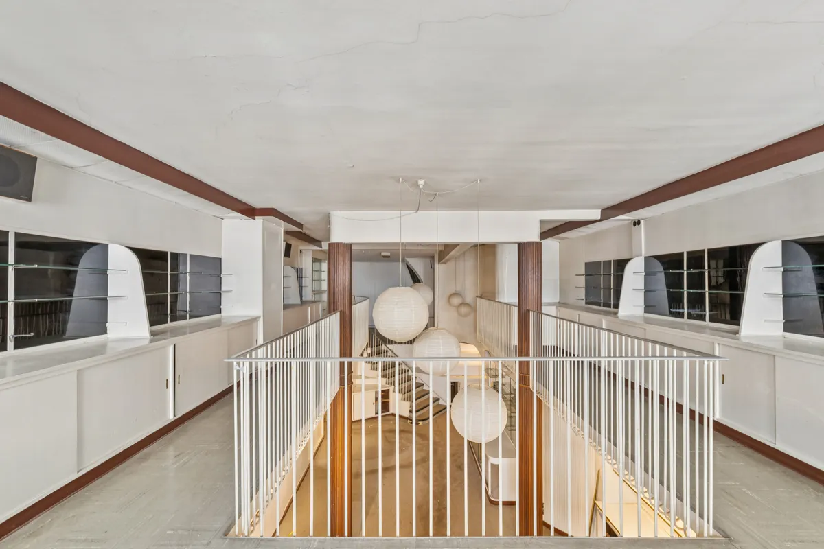 En stor indre atrium med hvide søjler og en hvid stige, hvor der hænger hvide lanterner i loftet