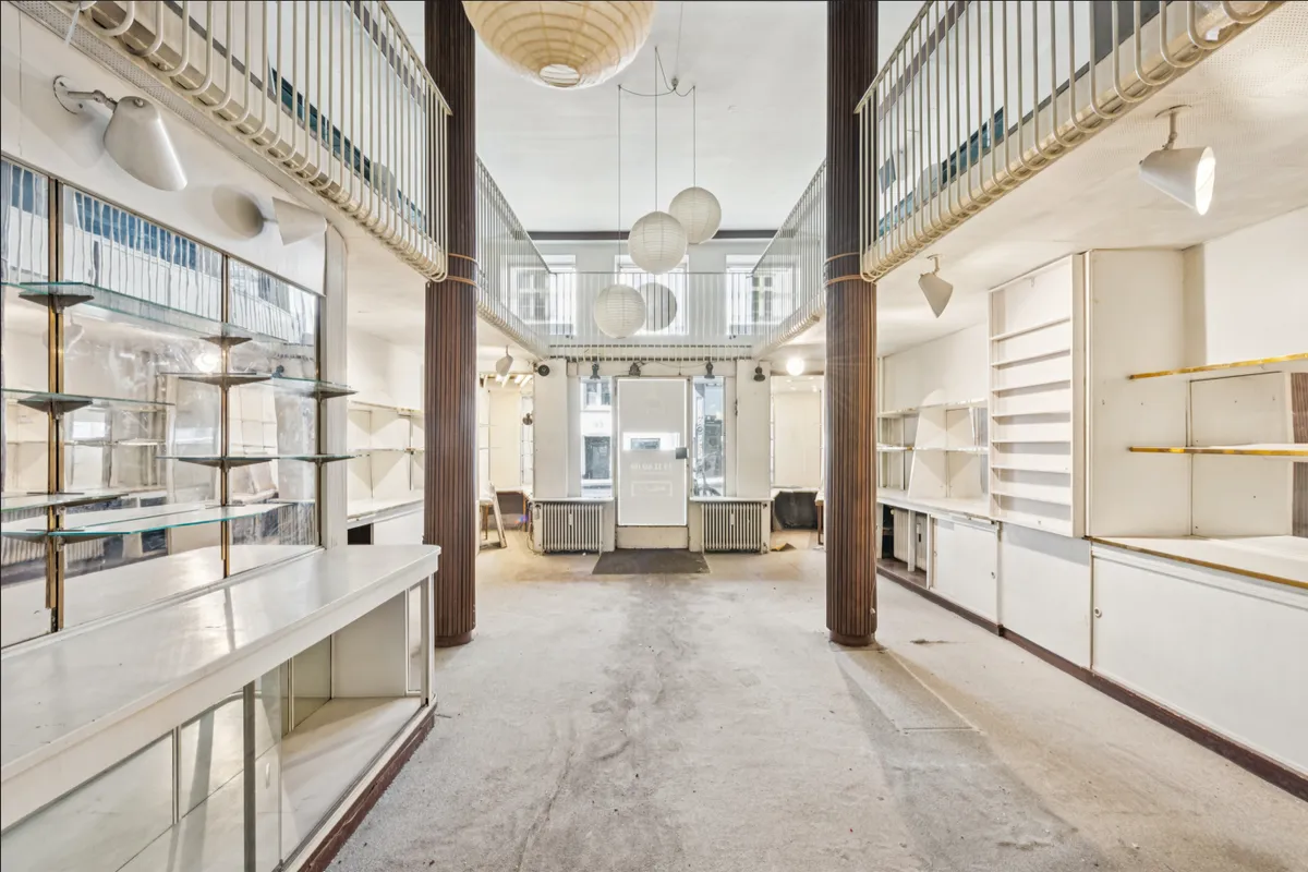 En stor lys stue med højt loft og store vinduer og lysekroner og hylder og stolpekonstruktioner