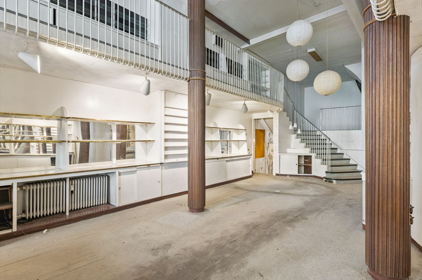 Indvendigt rum i Nørregade 30 med åbent design, loftshøjde, tre lyse lanterner, højt gulv og lyse gulvvægge samt stige til overetager