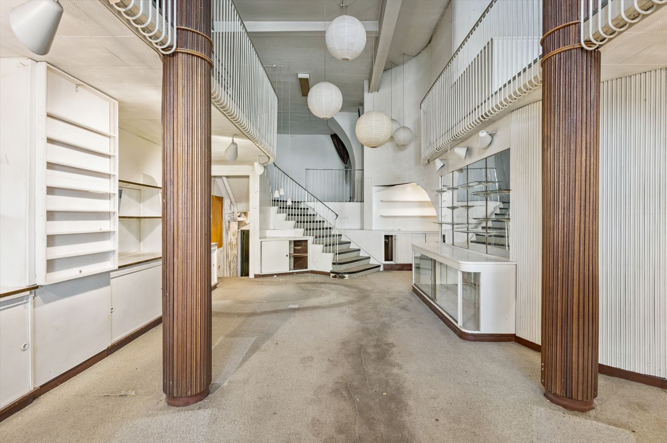 Lyst og indbydende rum med lysekroner, loftsvinduer og trapper. Ledig restaurant/detaillokale i københavnsk bygning.