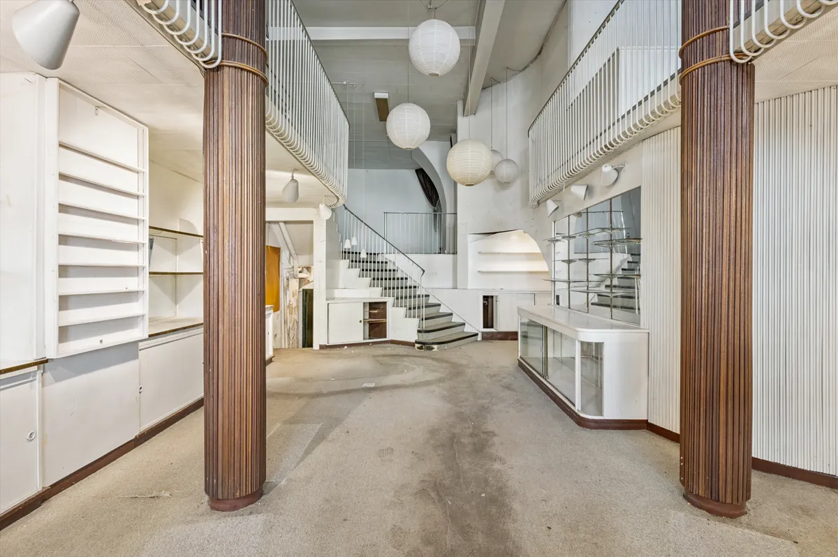 Lyst og indbydende rum med lysekroner, loftsvinduer og trapper. Ledig restaurant/detaillokale i københavnsk bygning.