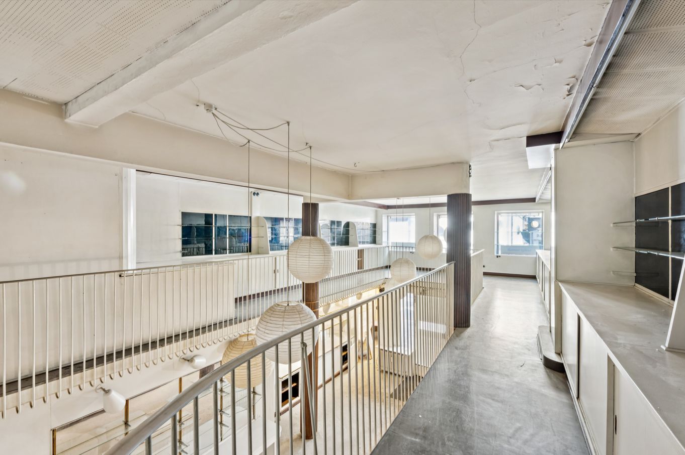 Indkøbsgalleri med store vinduer og højt loft, lysekroner, hvide vægge og gulve, hæklet gulv med lysekroner