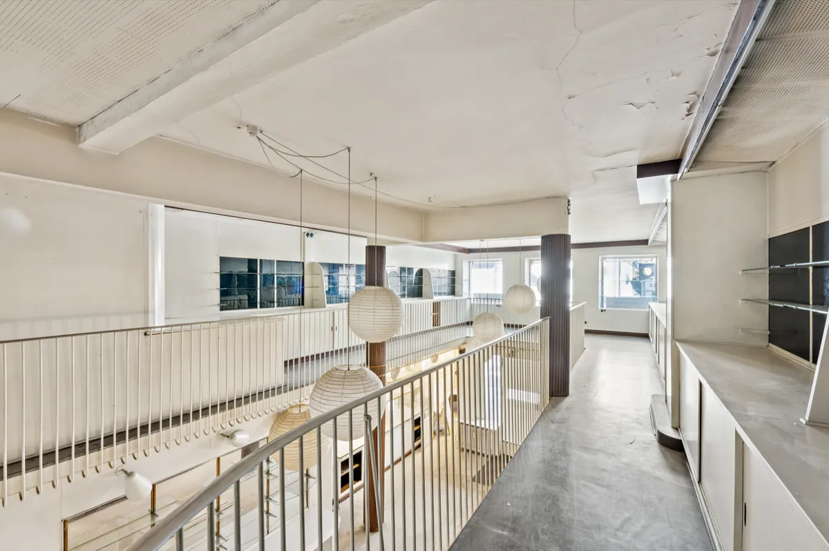 Indkøbsgalleri med store vinduer og højt loft, lysekroner, hvide vægge og gulve, hæklet gulv med lysekroner