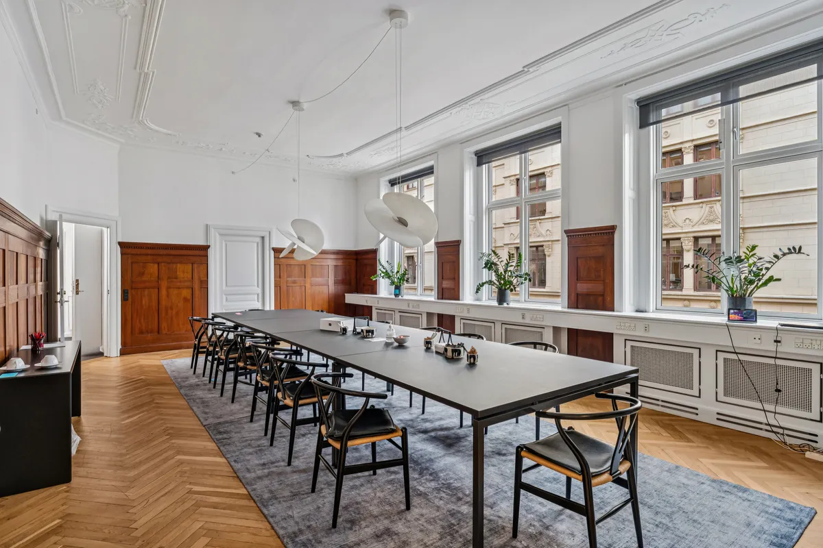 Herskabeligt kontor med elegant møblering, moderne skrivebord, møbler i lyse farver og moderne loftslampe samt en udsigt til byen.