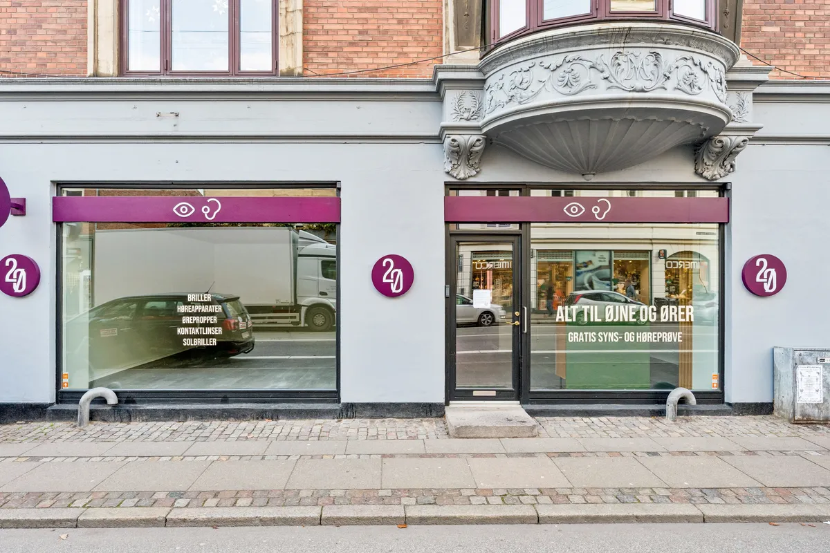 Et forretningslokal til leje på Gammel Kongevej 121, st. 1 med 162 m² og 58 m² kælder. Butikken har moderne vinduer og en stor dør med reklame for briller og brilletilbehør.