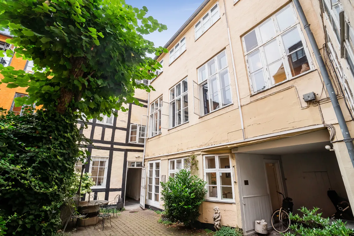 Kontor til leje på Store Kannikestræde med grønne planter og træer i baggården, møbler og en cykel parkeret udenfor