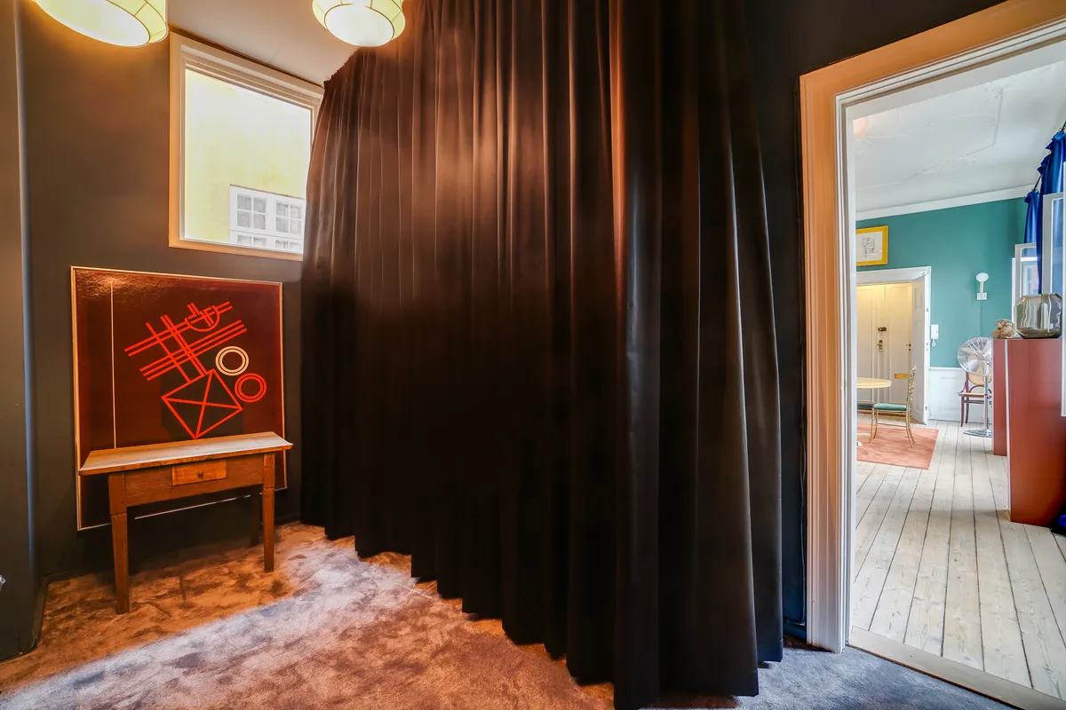 Moderne kontor med karminrød væg, tekstmaleri på brun bord og åbne døre til nærliggende værelser, hvor der er en lysegul væg og gult bord