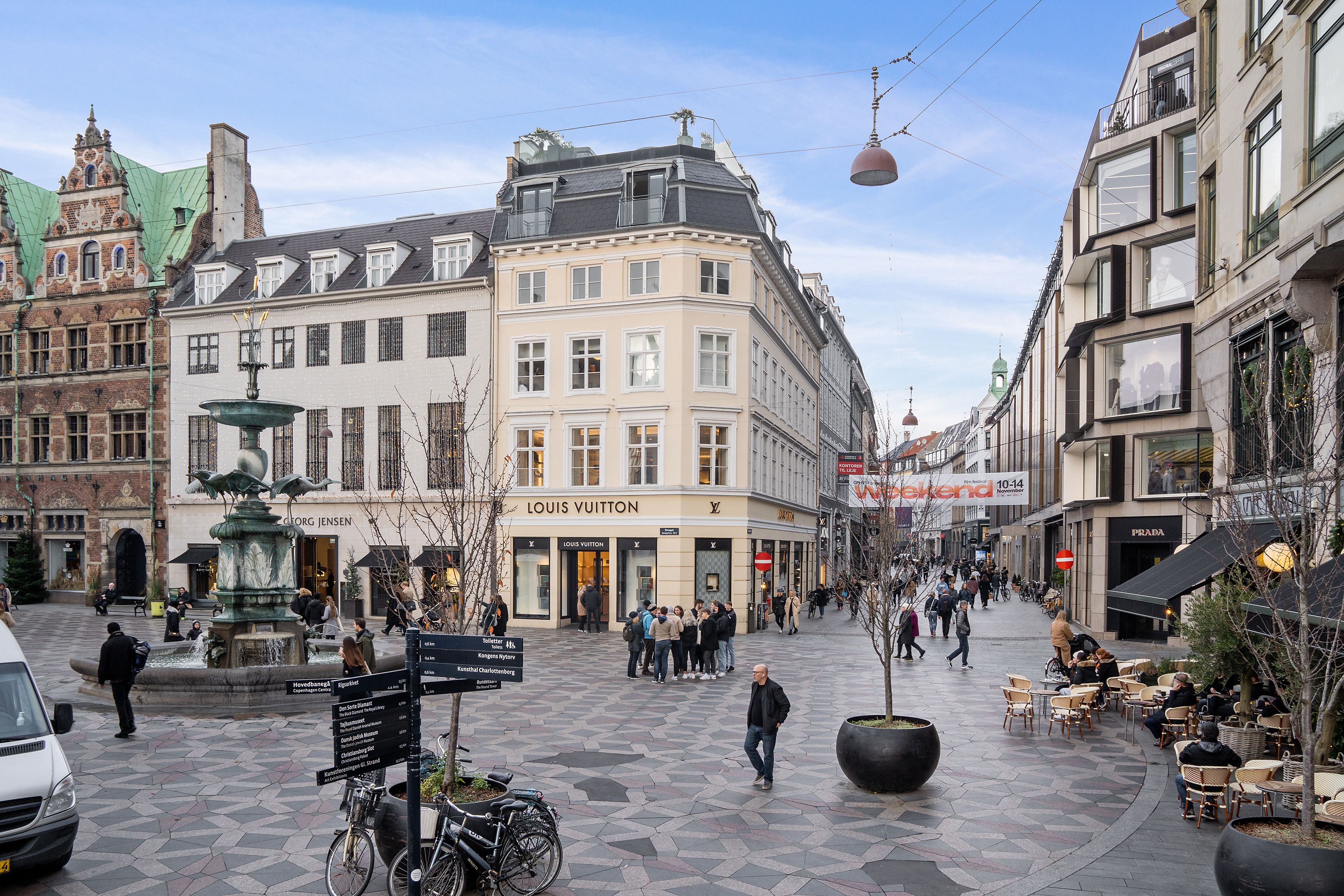 En kontorbygning på Købmagergade med Louis Vuitton butik, mennesker går rundt og nyder forretningsområdets atmosfære.