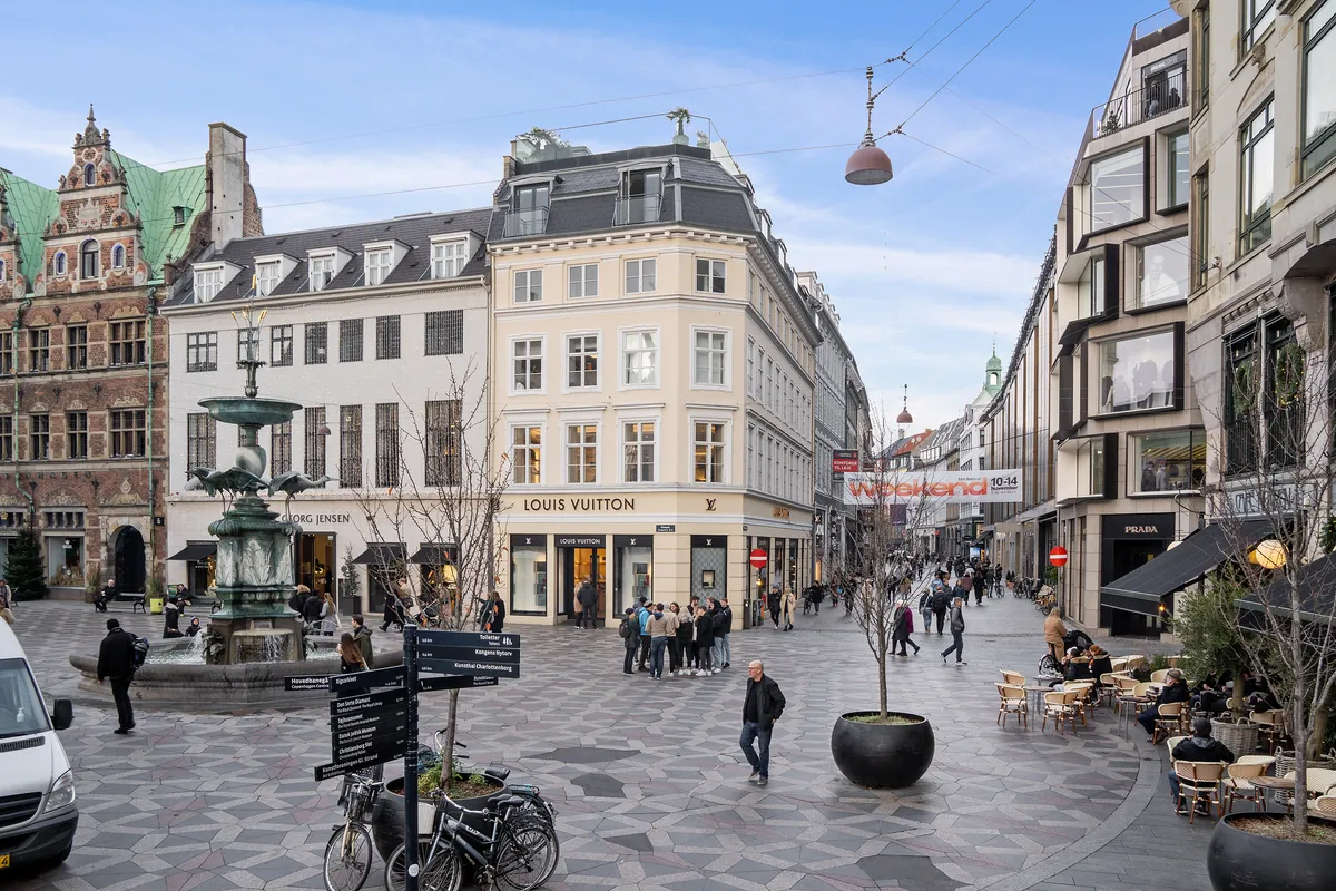 En kontorbygning på Købmagergade med Louis Vuitton butik, mennesker går rundt og nyder forretningsområdets atmosfære.
