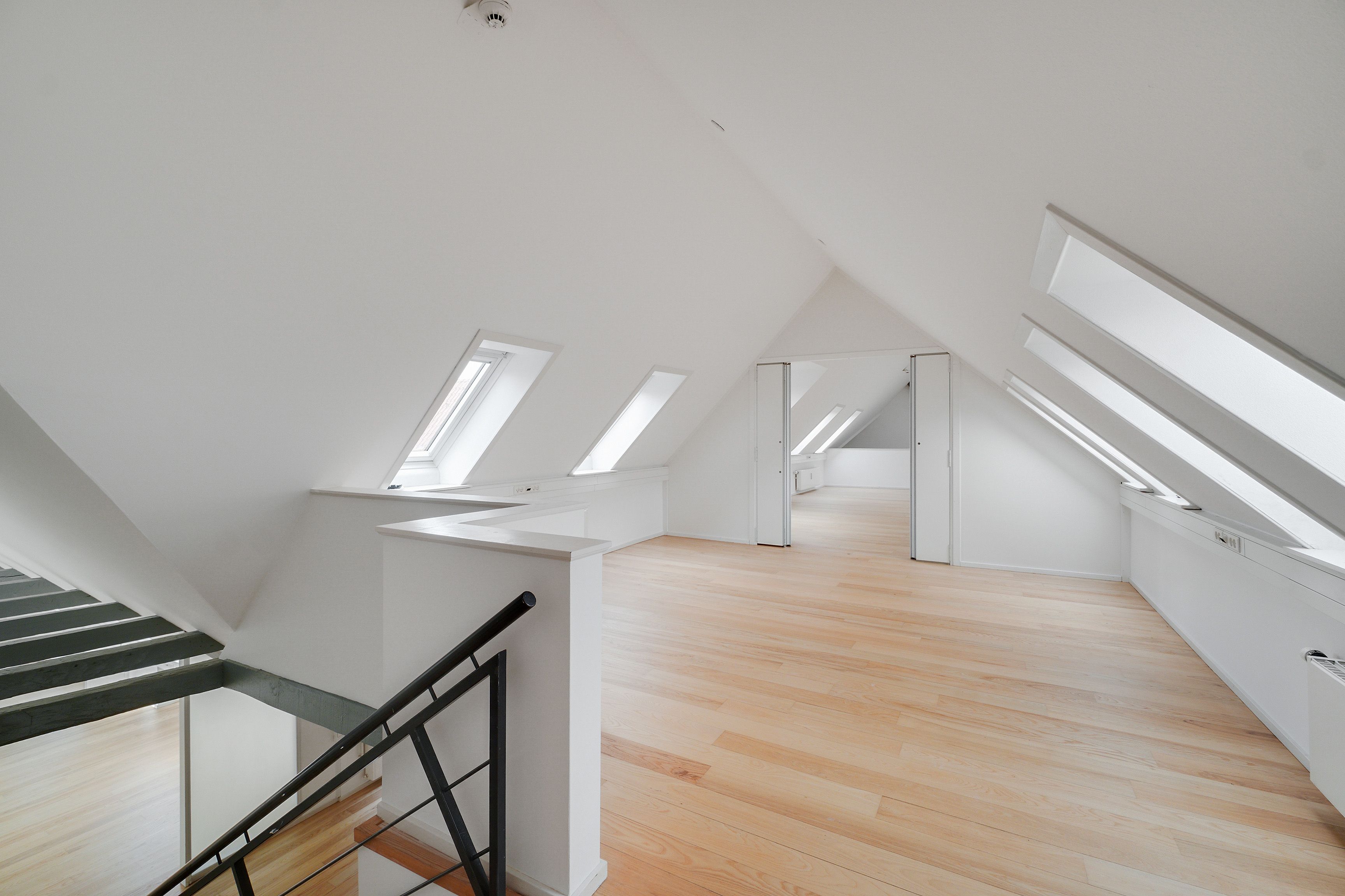 Et stort loftsrum med høje lofter og lyse loftsvindue. Store lysevinduer og lyse lofter. Moderne loftsvinduer. Lyst og luftigt loftsrum med tre loftsvinduer og hvide vægge