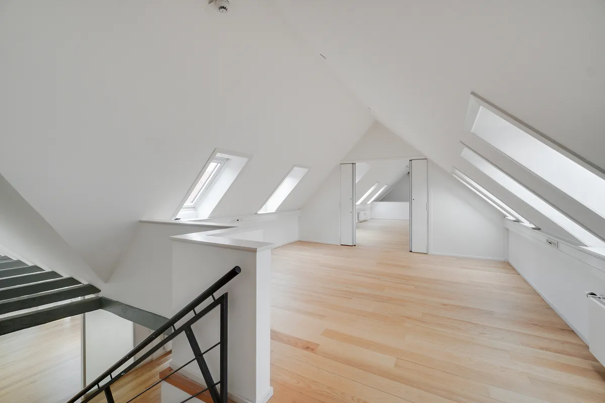 Et stort loftsrum med høje lofter og lyse loftsvindue. Store lysevinduer og lyse lofter. Moderne loftsvinduer. Lyst og luftigt loftsrum med tre loftsvinduer og hvide vægge