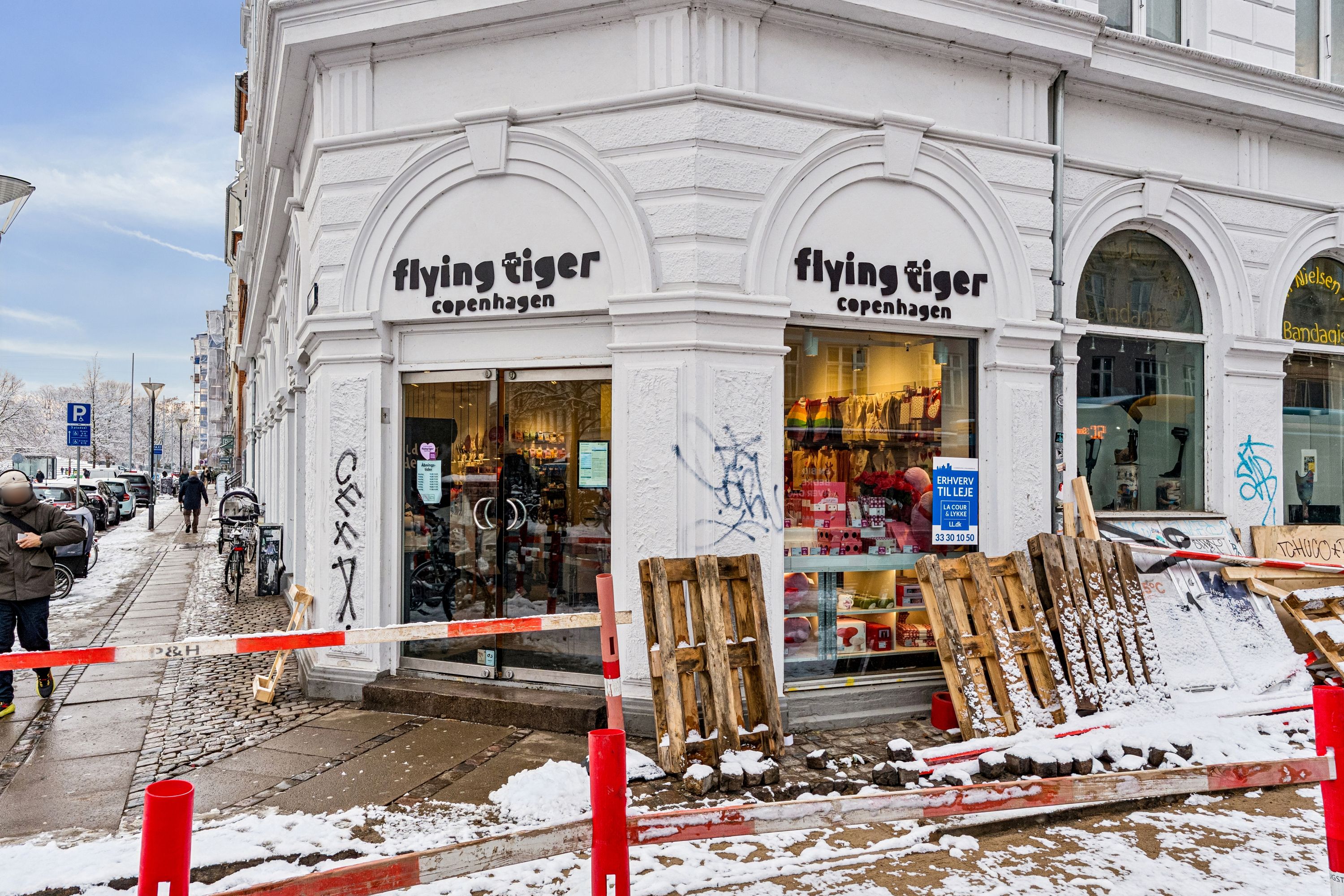 Forretningslejemål til leje på Frederiksborggade 23, 1360 København K. Butik med vinduer og graffiti på facaden. Gangstier og snedækket.