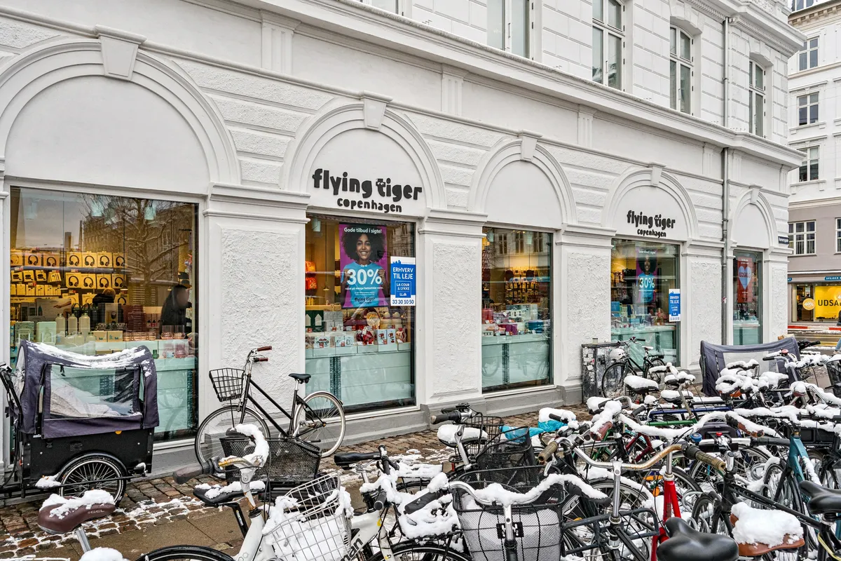 Flyvende tiger butik med 30% rabat og mange cykler med sne derinde og en cykelvogn med sne på gaden