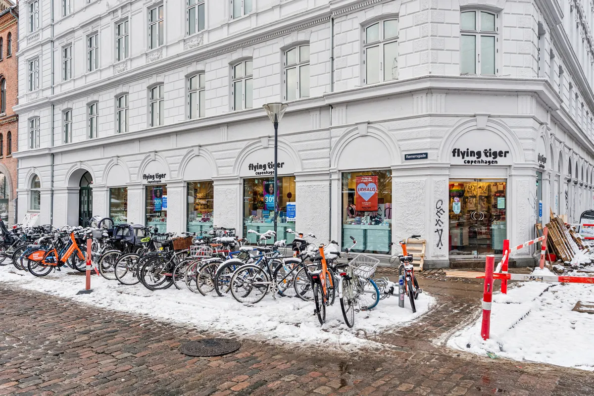 Butiksforretning med Flying Tiger på Frederiksborggade i København med flere cykler parkeret foran og sne på jorden