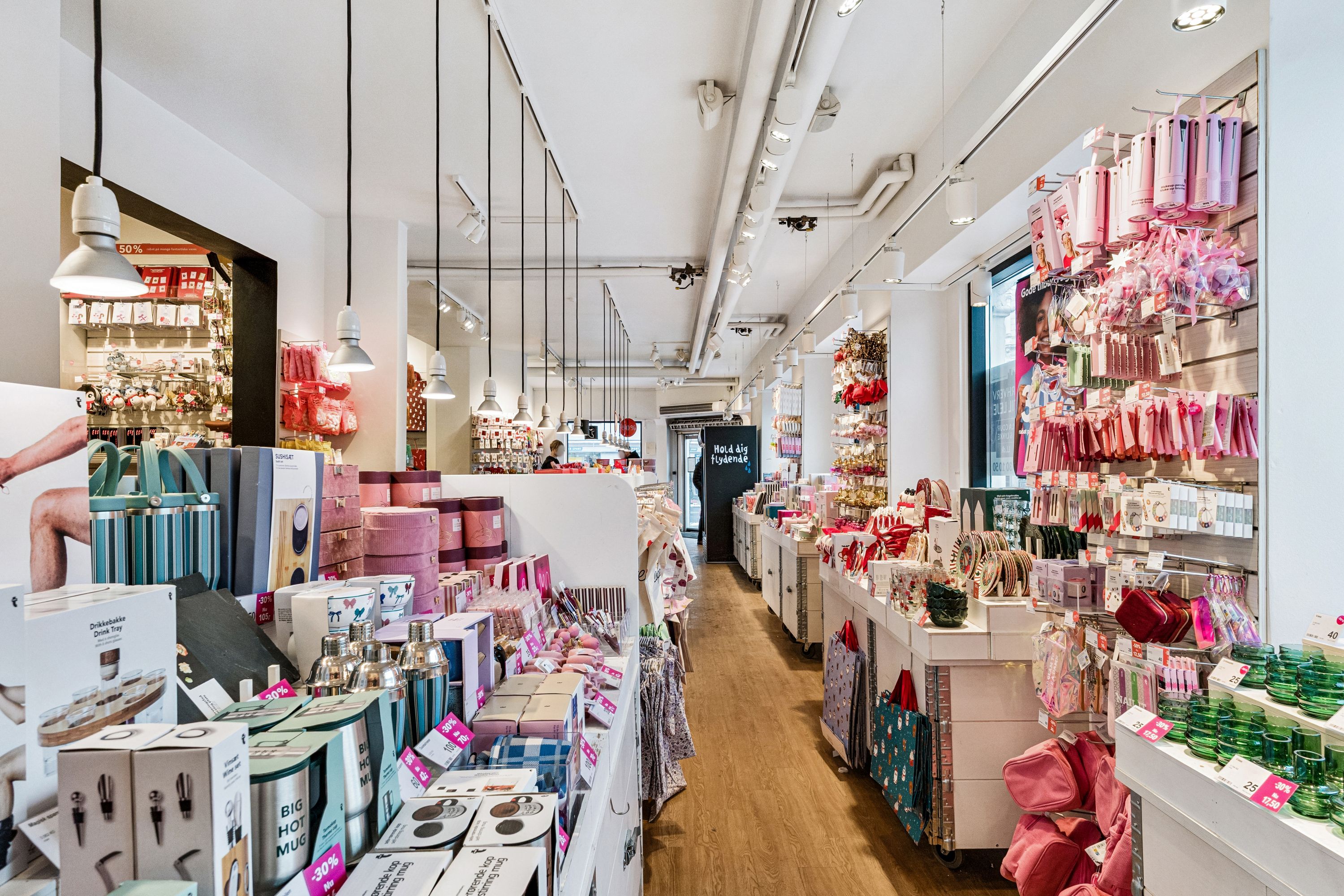 En butik med luksuriøse gaver og smykker, der er godt oplyst med hængende lamper, og alle produkter er pænt opstillet og præsenteret for kunderne