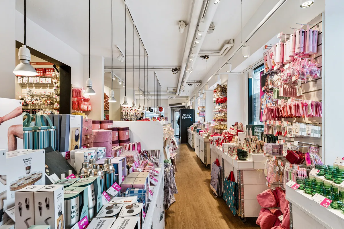 En butik med luksuriøse gaver og smykker, der er godt oplyst med hængende lamper, og alle produkter er pænt opstillet og præsenteret for kunderne