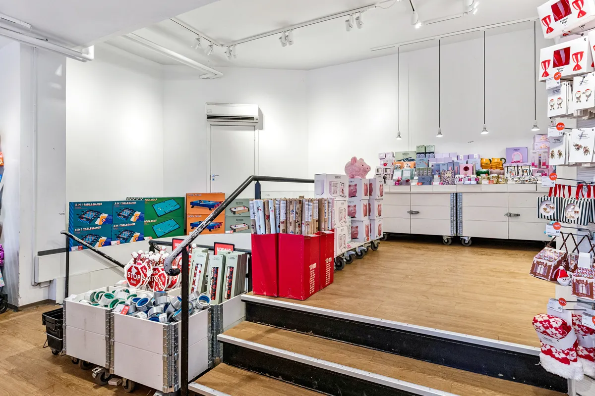 Lejemejlighed i København med nyt gulv og gulvvarme, samt et stort vindue og hængende lysekroner. Butikken med køkkenartikler og gaveartikler samt flere pigefigurer og salgsfremmende plakater