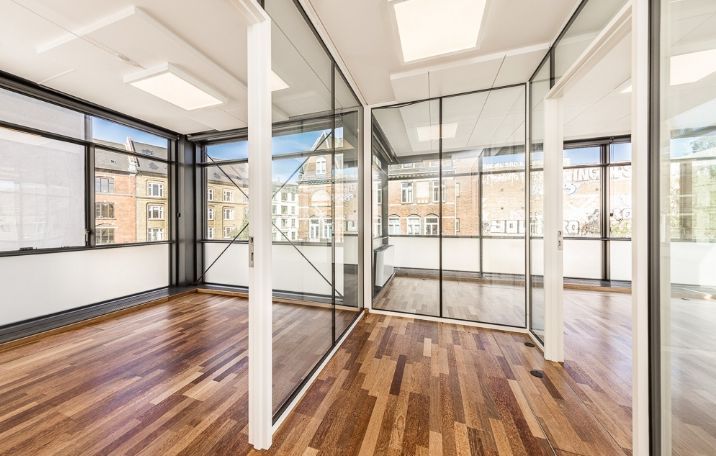 Moderne kontor med glasvinduer, højloft og trægulv. Lejemål på Nørrebro med adgang til fælles gård.