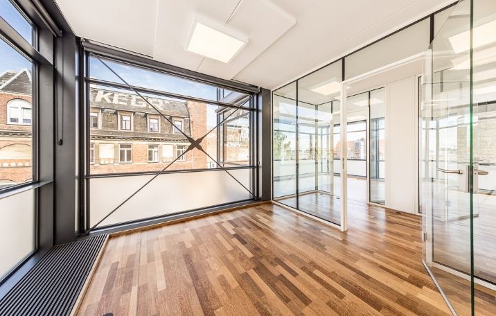 Kontor i miniskyskraber på Nørrebro med glasvinduer og hårdt trægulv samt udendørs gårdhave med solbelysning
