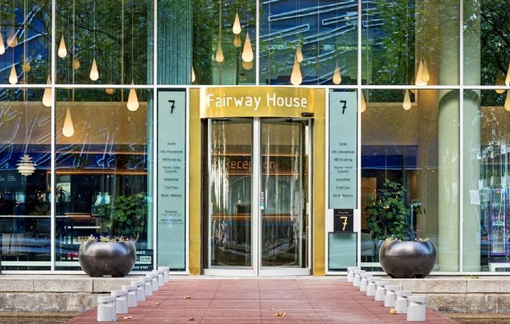 Fairway House på Arne Jacobsens Allé 7 i København. Bygningen med moderne glas og plantager og en indgang med guldsorte vinduer