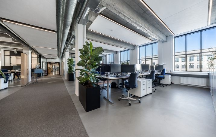 Kontor med moderne indretning, højt til loftet, lyse vinduer og fælles kontormøbler