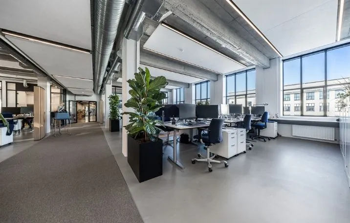 Kontor med moderne indretning, højt til loftet, lyse vinduer og fælles kontormøbler