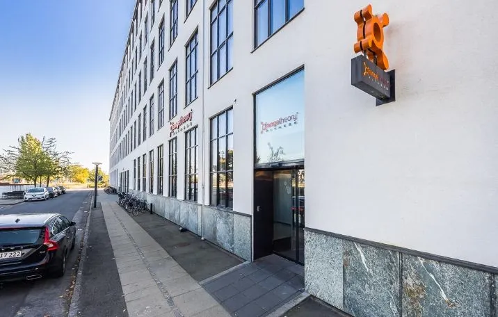 Fitnesscenter på Prags Boulevard med orange logo, glasvinduer og lejemuligheder for parkeringspladser og omklædningsrum