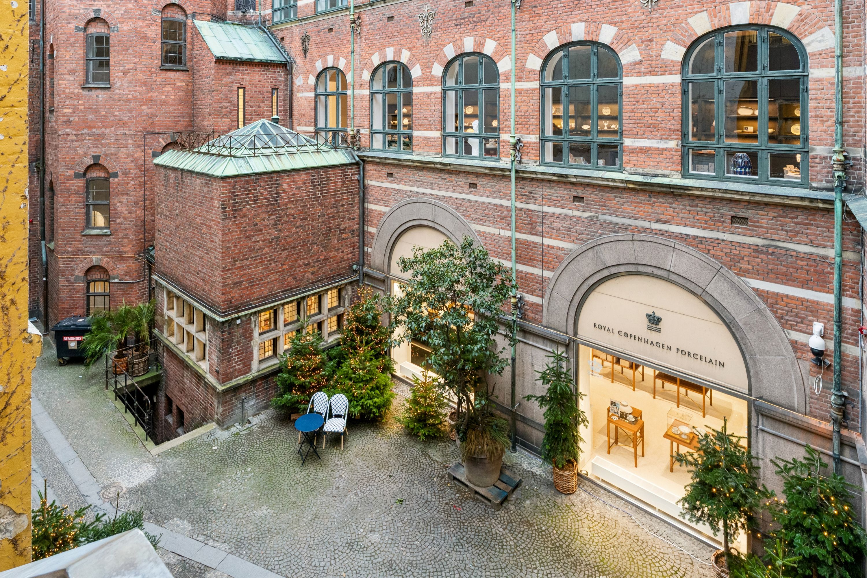 Kontor til leje i Købmagergade med flot gårdsplads, hvor der er nytårstræer og møbler. Inde i butikken er der Royal Copenhagen porcelæn.
