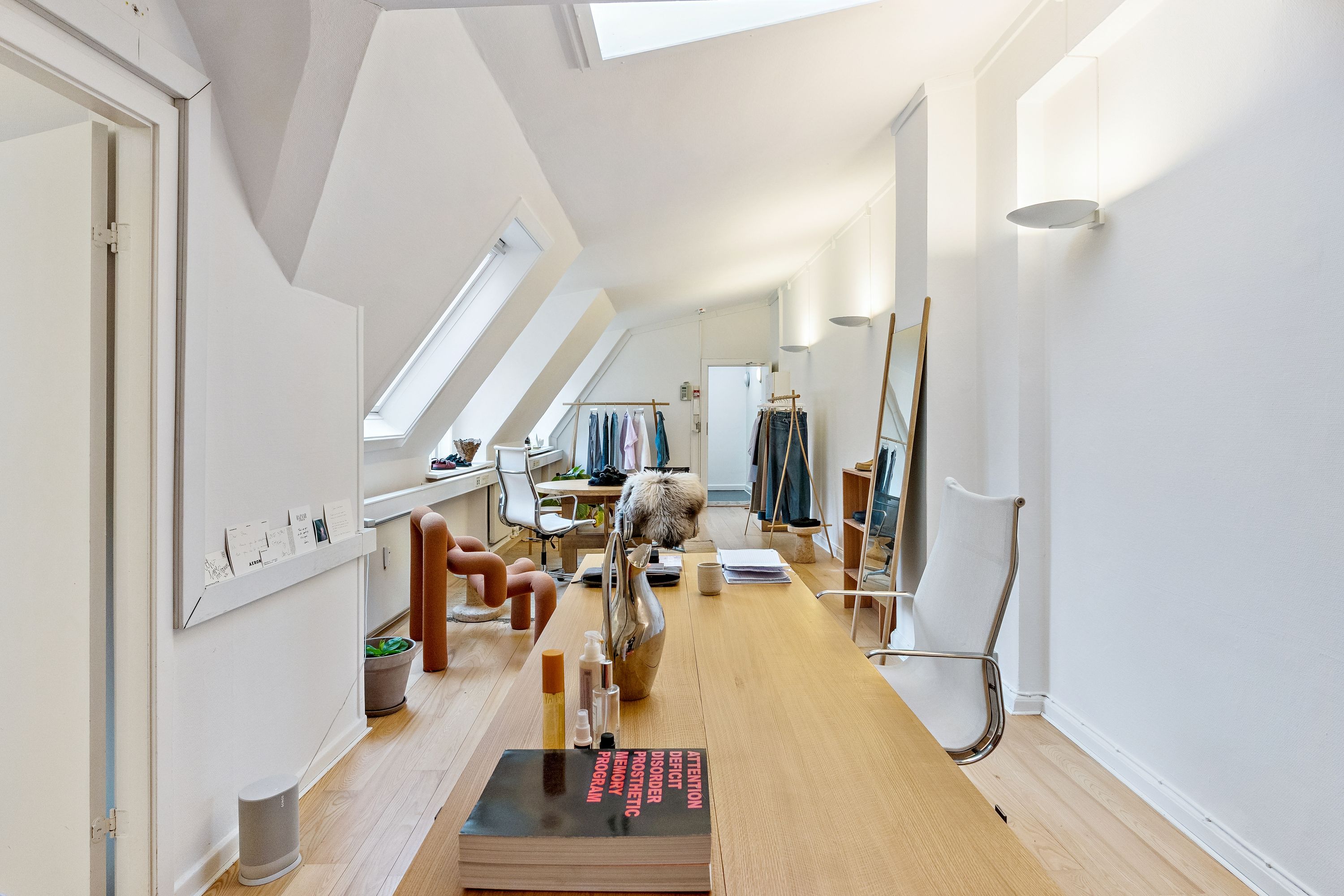 Et meget stilfuldt og luksuriøst kontor med højloft, lyse loftsvinduer og moderne møbler. Der er en stor bord, en stol og et køkken med en højstol og en høj.