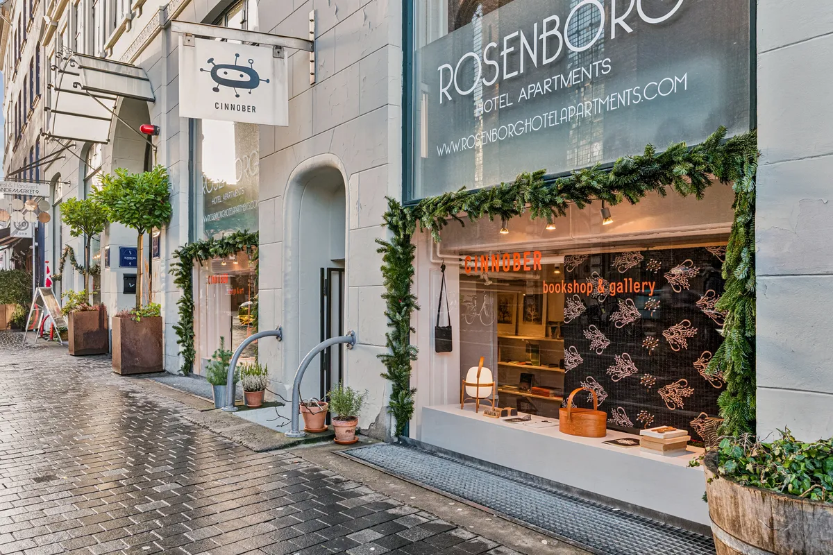 En københavnsk gade med bokse og krydderplanter. Butikken Rosenborg Hotel Apartments har en indretning med juletræer og bøger.