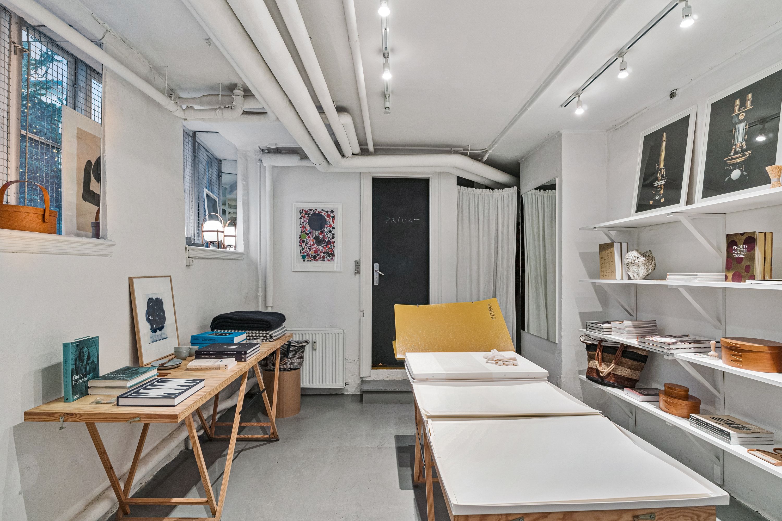 Butikslokaler med møbler og bøger på hylderne og en stor skrivebord med bøger og briller