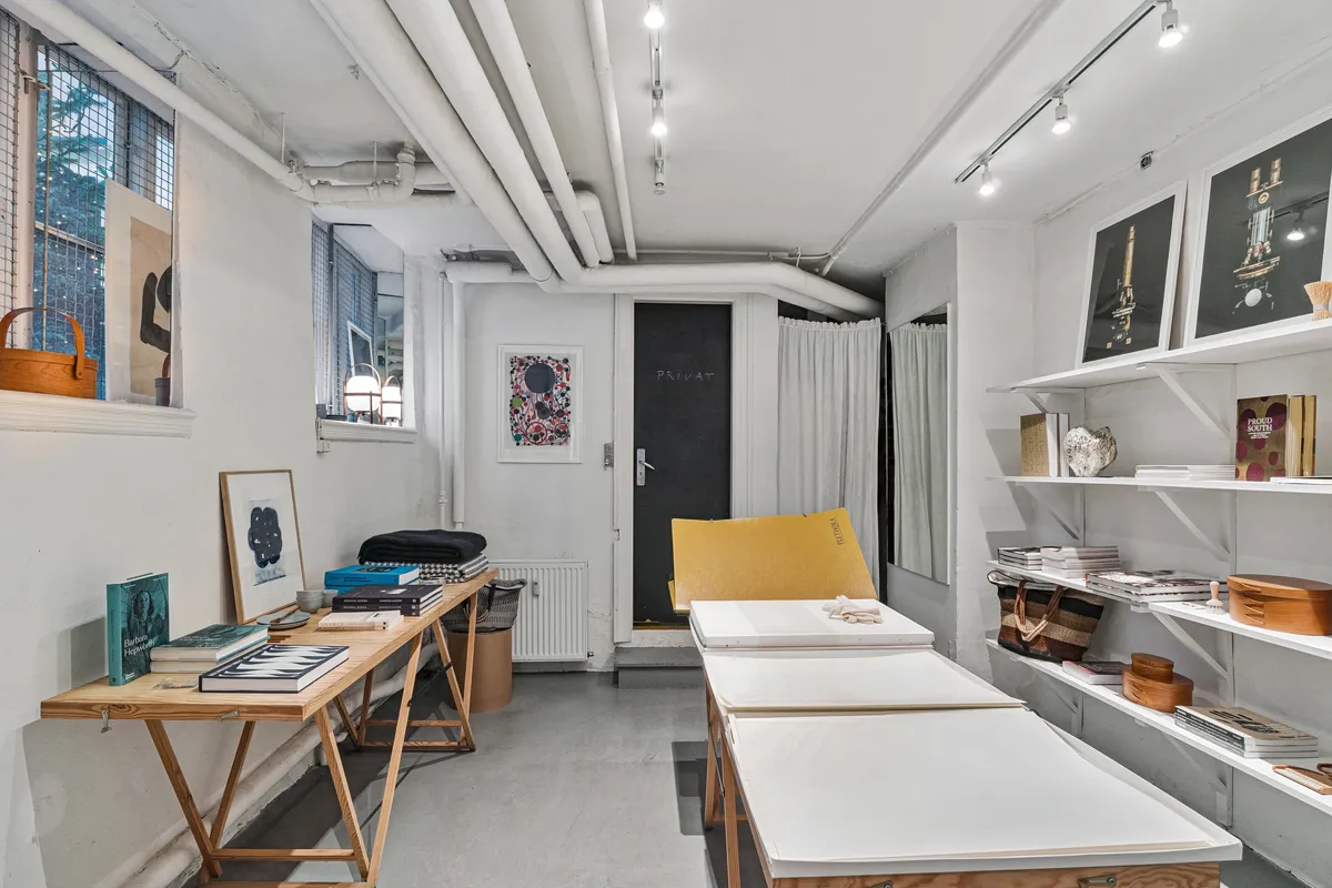 Butikslokaler med møbler og bøger på hylderne og en stor skrivebord med bøger og briller